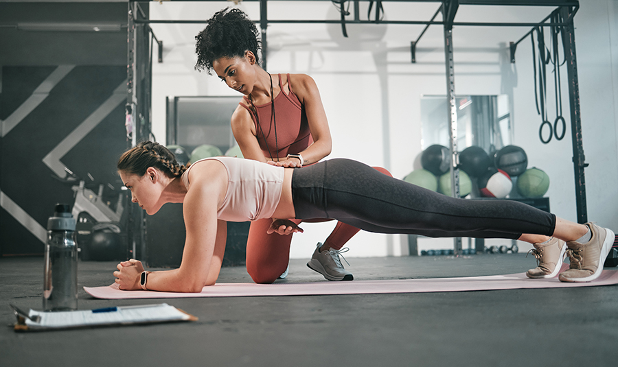 A female trainer assists woman with push ups